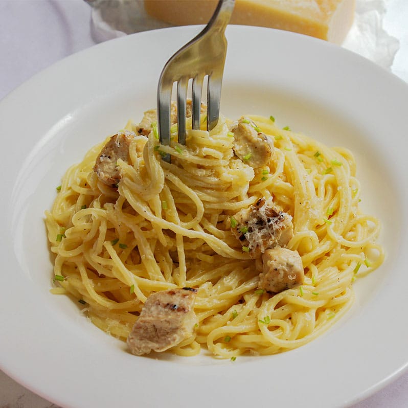 creamy low calorie alfredo sauce in a white plate with juicy chicken.