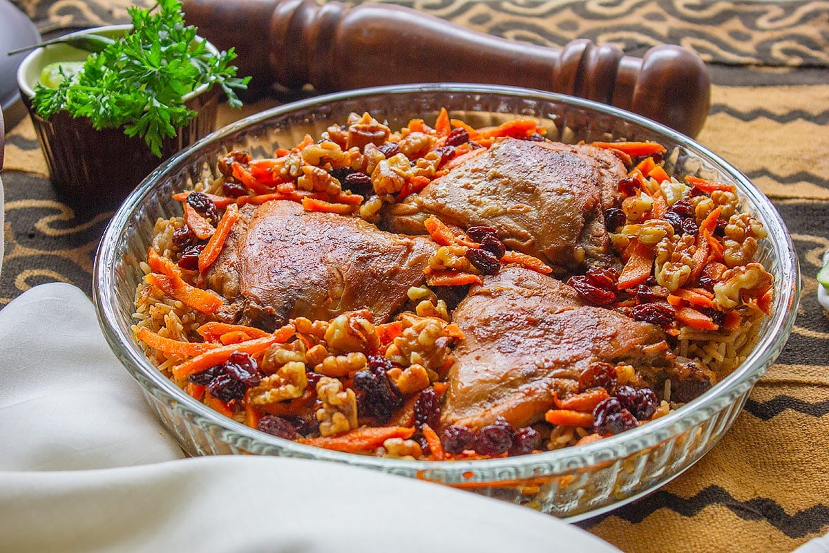 Afghani Pualo served in a glass bowl, garnished with raisins and fried carrots.