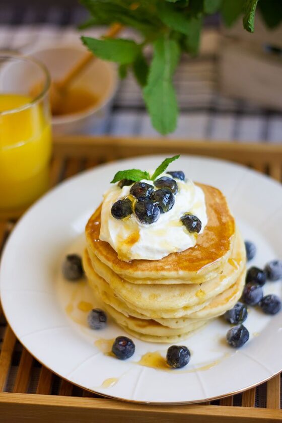 Two stacks of yogurt pancakes with syrup and butter