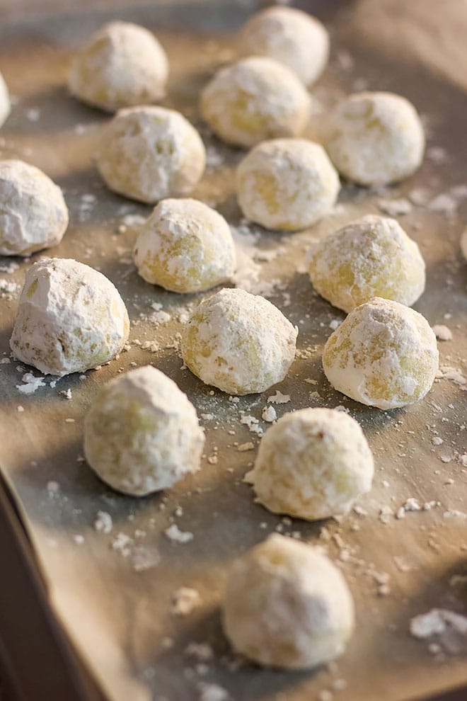 Freshly baked Russian tea cakes on baking sheet.