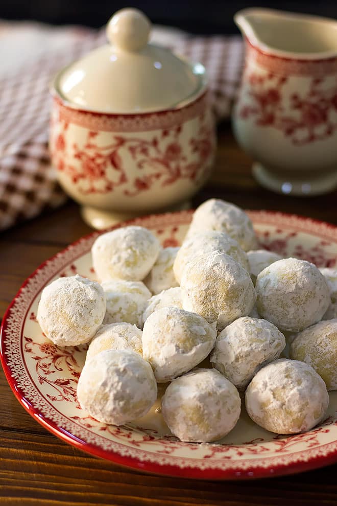 Side image of Russian tea cakes served on a red and white plate.