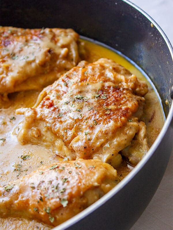 Smothered chicken in a black iron skillet.