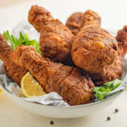 Southern fried chicken served in awhite bowl with lemon slices. Close up image.