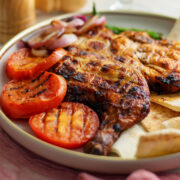 Grilled Spatchcock Chicken served with grilled tomatoes and onion.
