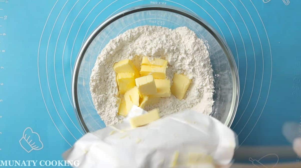 Adding chilled butter to the flour mixture.
