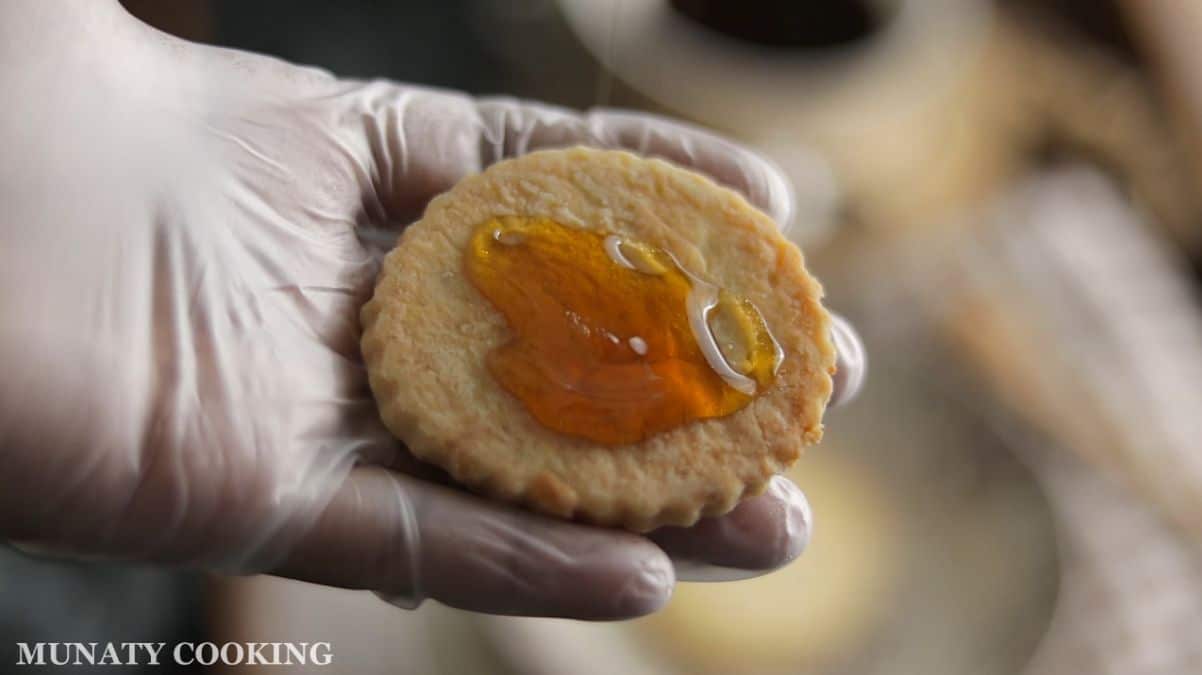 Adding honey to the bottom of one cookie to make a sandwich cookie.