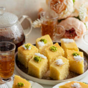 Revani cake slices served in a plate with tea on the side.
