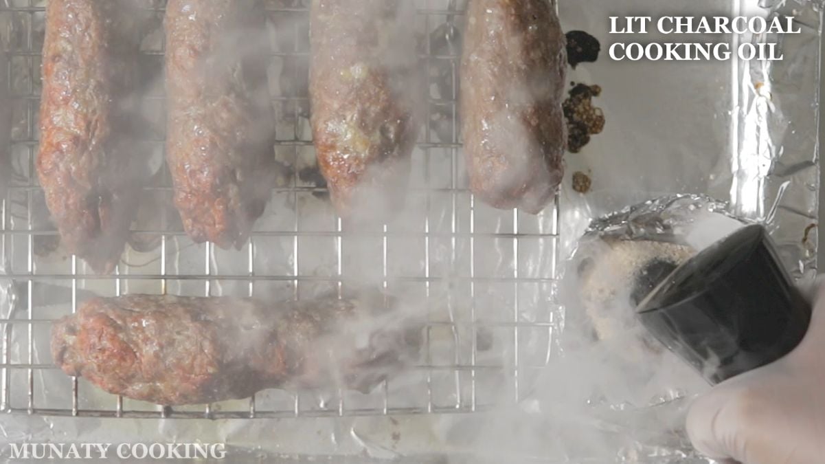 Spraying a lit charcoal with oil for the smoking flavor.