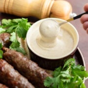 Tahini sauce served in a brown small bowl with a spoon.