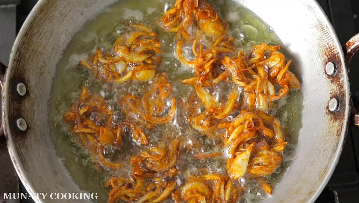 Frying the onion pakoras until golden and crispy.