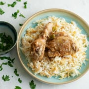 Juicy chicken stew on fluffy rice served on a light blue plate.