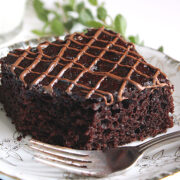 Eggless Nutella Chocolate cake slice served on a small plate with a fork on the side.