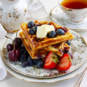 Blueberry waffles served with fruits on a plate.