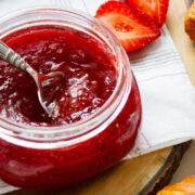 Strawberry refrigerator jam in an open small glass jar.