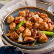 Close up image of cashew chicken served on a plate and garnished with spring onion.