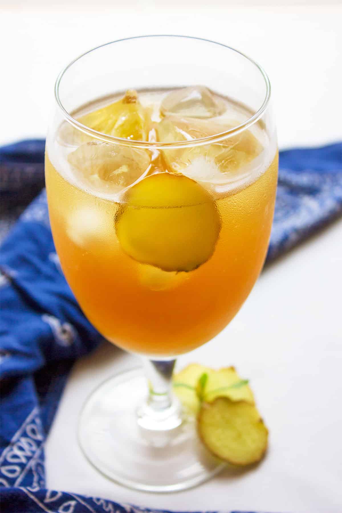 Iced tea with lemon and ginger in a glass with ice cubes.