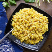 Lime rice served in a black plate garnished with pine nuts.