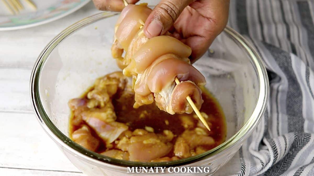 Threading the chicken thighs on wooden skewers.