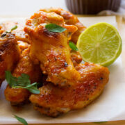 Brown Sugar BBQ Chicken Wings served with a slice of lemon on parchment paper.