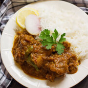 Achari gosht served with rice and slice of lemon.