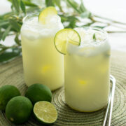 Brazilian lemonade served in two glasses with ice cubes and slices of lime.