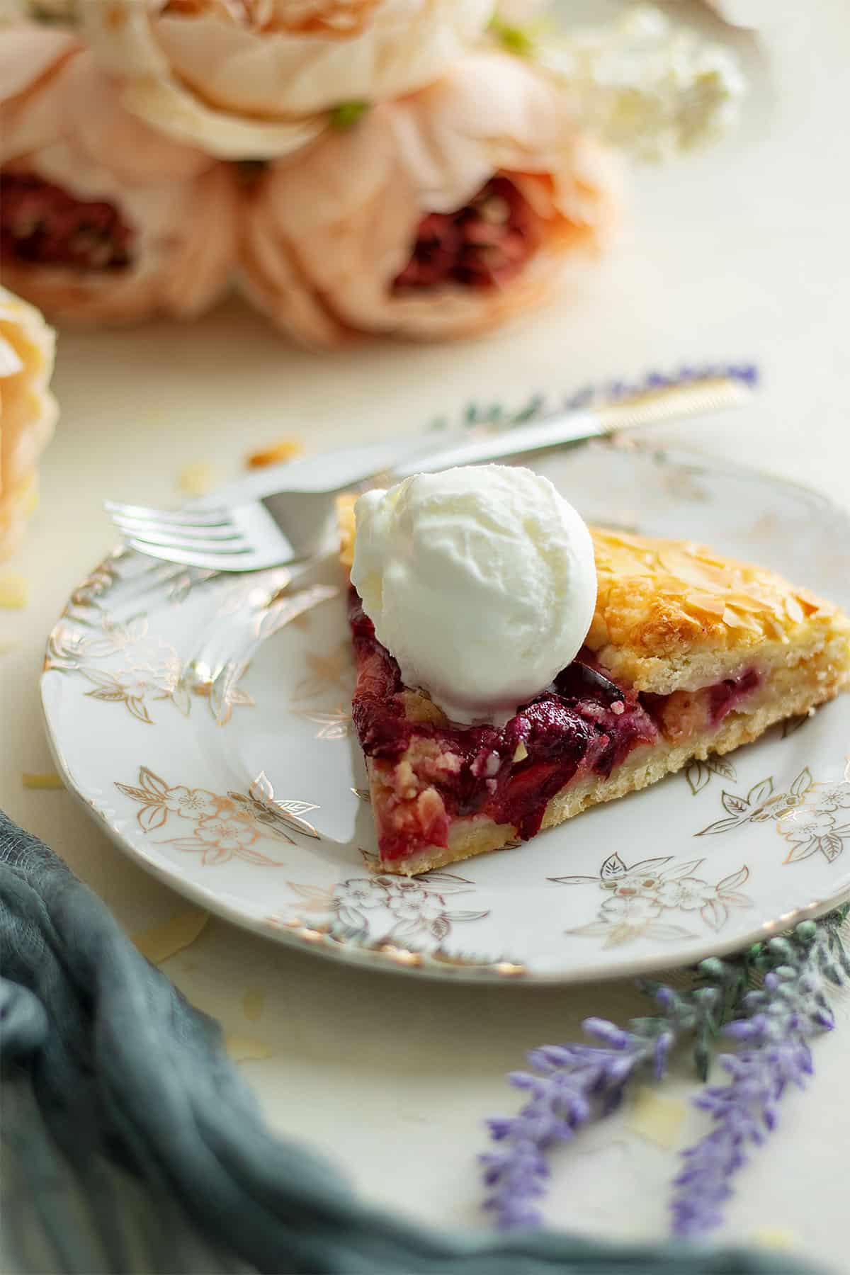 Showing a slice of plum galette with frangipane and a scoop of ice cream.