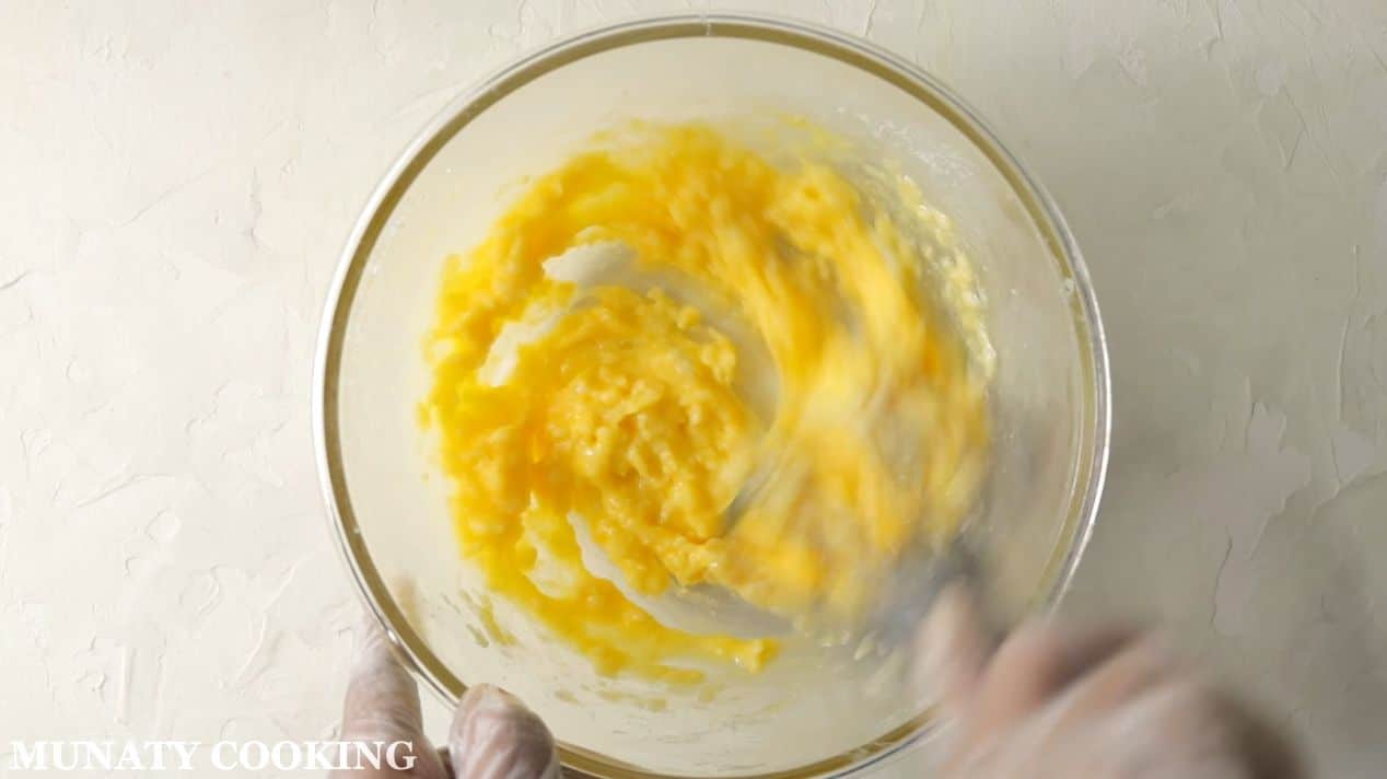 Beating an egg with sugar and butter.