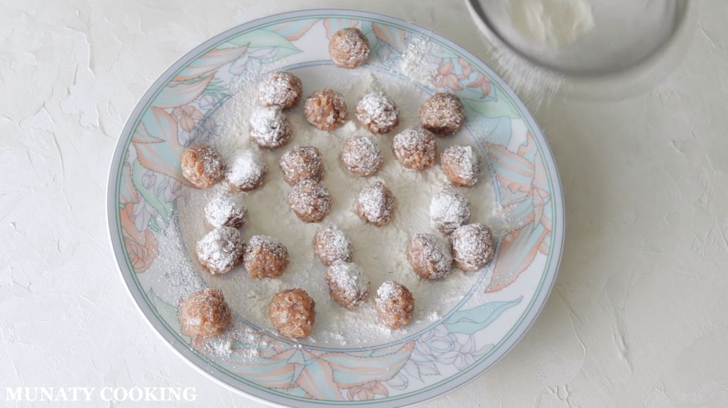 Coating mini meatballs with flour.