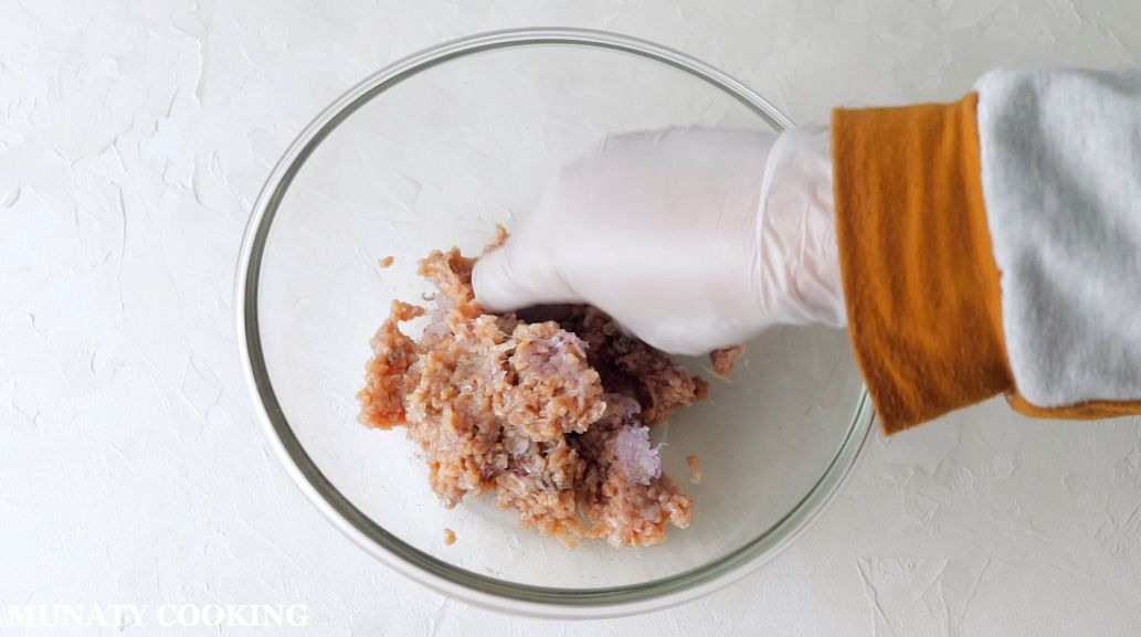 Mixing ground beef with onion in a bowl.