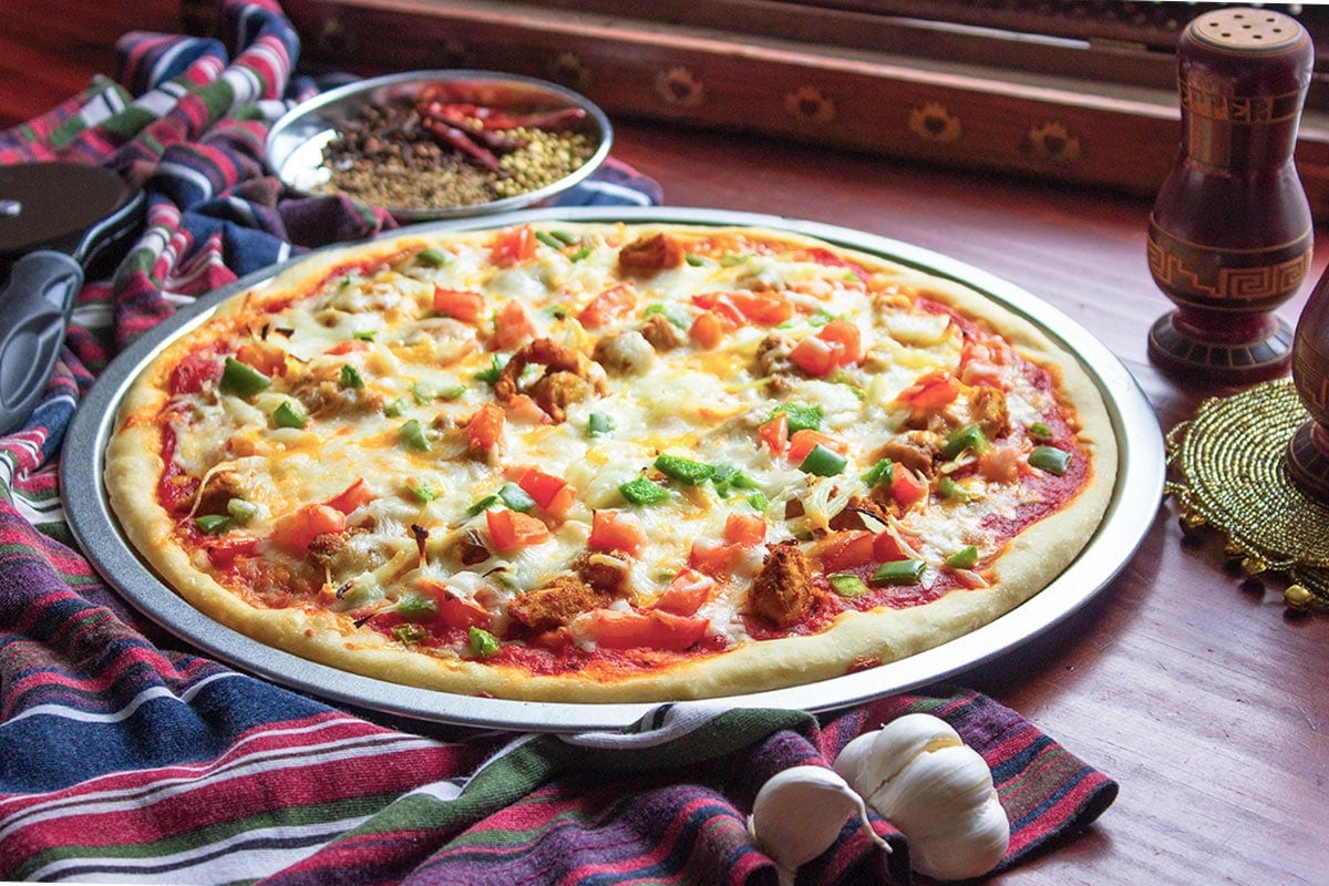 Chicken tikka pizza, served on a pizza flat pan.