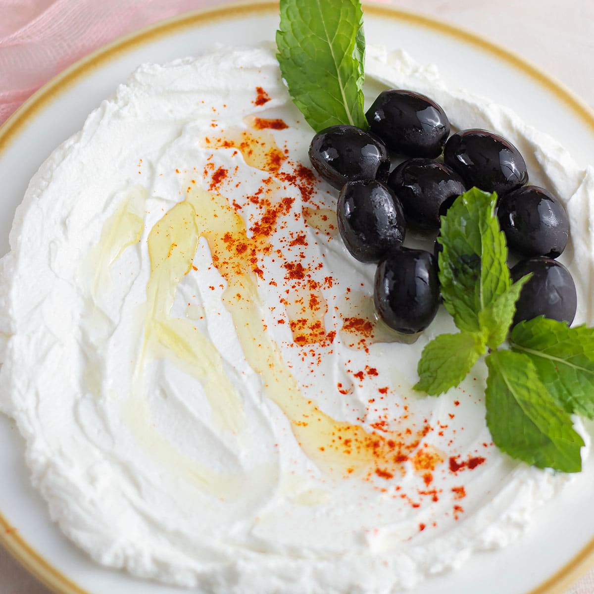 Homemade fresh labneh feature image, showing Lebanese Labneh in a white plate with olives and mint leaves.